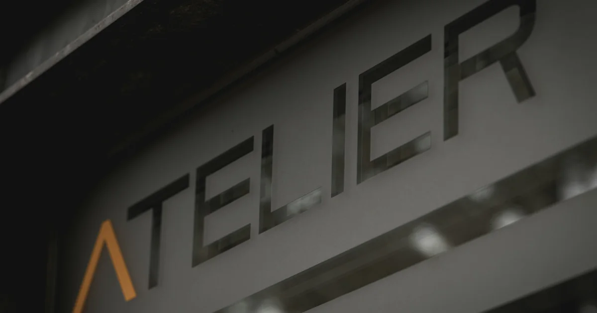 Close-up of an atelier sign with a stylised orange letter on a dark wall